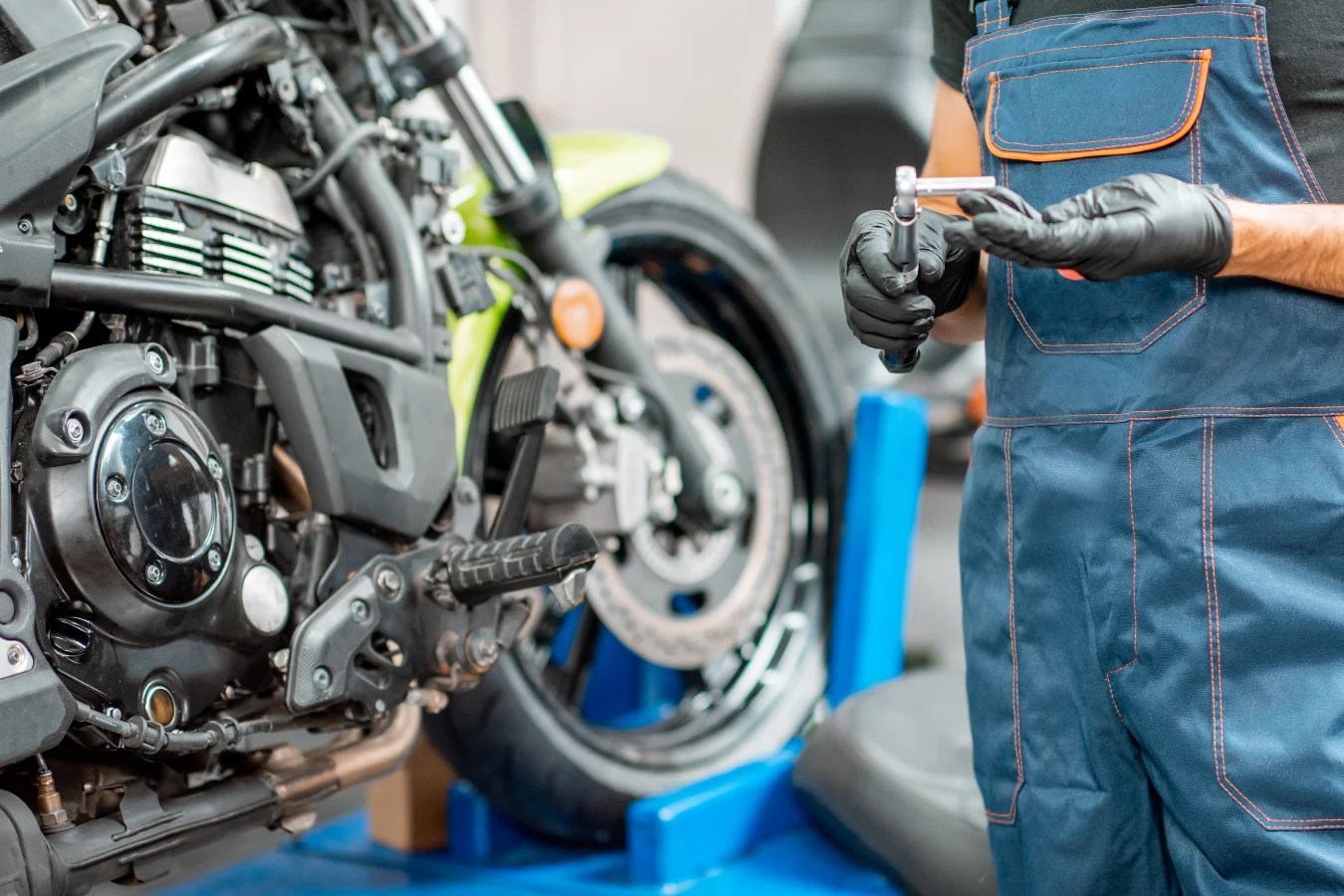 A mechanic with a wrench beside a bike up on the stand